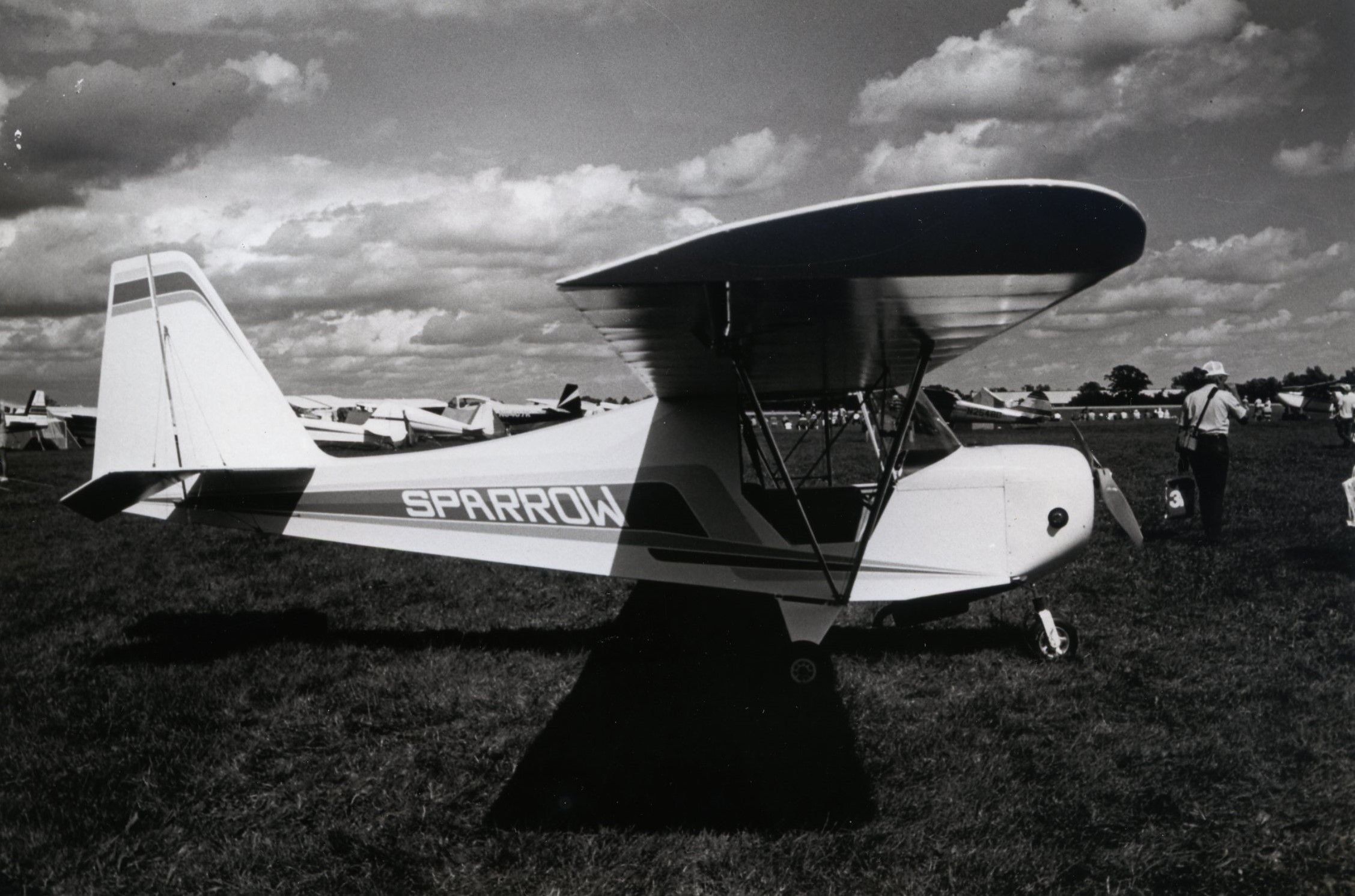 Black-and-white photograph of a Carlson Sparrow parked on the grass at a fly-in