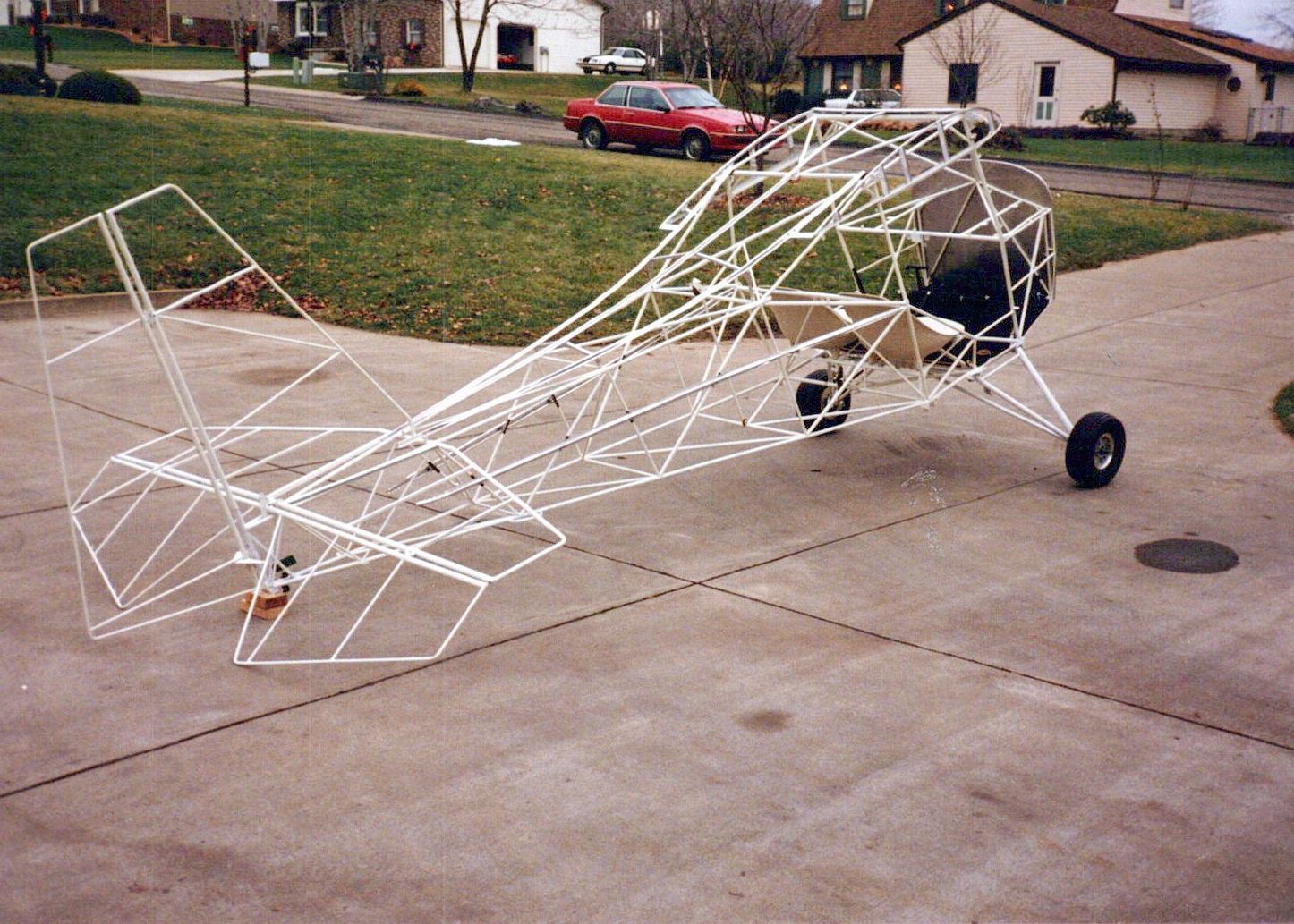 Bare welded steel-tube fuselage frame of a Carlson Sparrow on its landing gear in a driveway