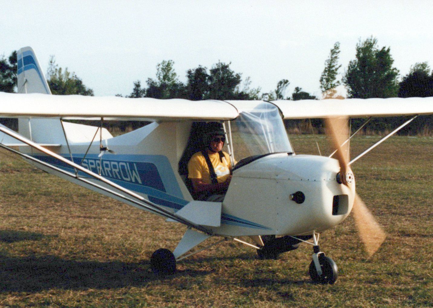 Pilot seated in a Carlson Sparrow Ultralight on a grass strip